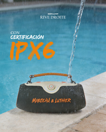 Altavoz portátil Rive Droite de Marceau & Luthier junto a una piscina, recibiendo un chorro de agua para demostrar su certificación de resistencia IPX6.